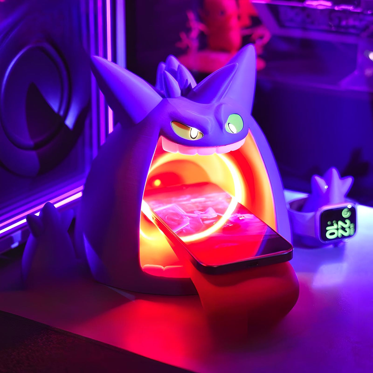 Neon desk setup with Gengar-inspired wireless charger, phone charging on angled stand with glowing LED ring, smartwatch dock nearby