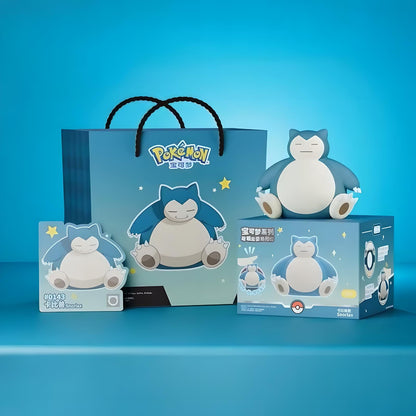 Snorlax-inspired night light with gift box and shopping bag packaging on blue background