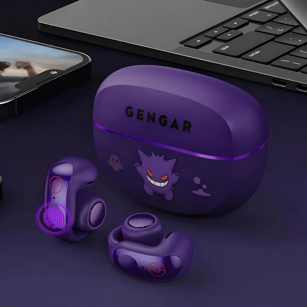 Gengar purple open-ear wireless earbuds with charging case on desk beside laptop and phone
