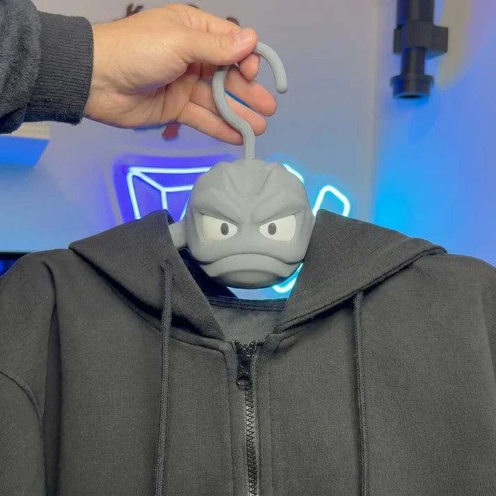 A hand holding a 3D-printed Geodude hanger to hang a heavy black zip-up hoodie jacket.