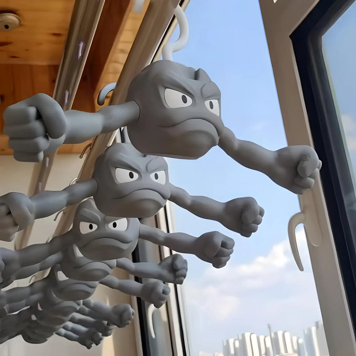 A row of multiple gray Geodude coat hangers hanging from a laundry rack by a sunny window.